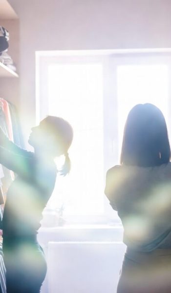 Two people organizing a closet with sun rays flooding in from the window behind them
